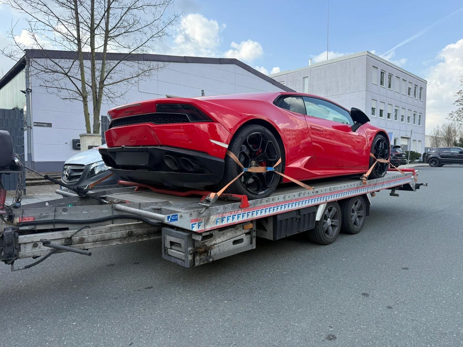 Roter Lamborghini Huracán in Heckansicht, mit Spanngurten auf Anhänger gesichert
