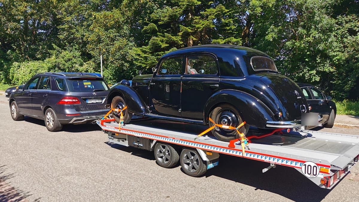 Schwarze Mercedes-Benz-Oldtimer-Limousine mit Spanngurten auf Autotransportanhänger gesichert