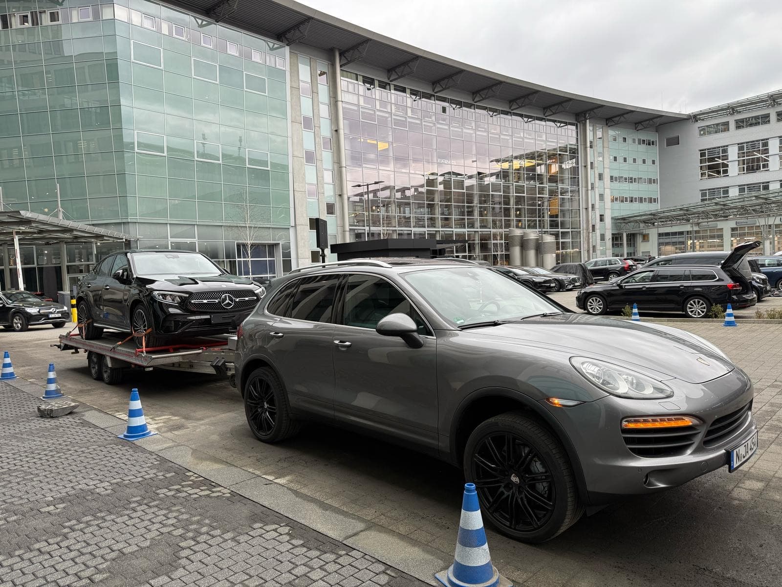 Grauer Porsche Cayenne mit Anhänger und schwarzem Mercedes-Benz GLC Coupé